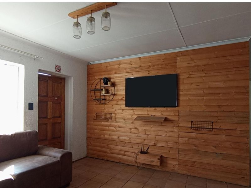 Living room featuring a prominent timber-clad feature wall, tiled flooring, and a solid timber entrance door.