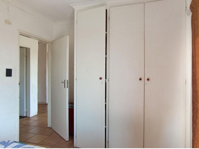 Bedroom featuring built-in cupboards and tiled flooring, requiring cosmetic updates to improve the overall finish and aesthetic appeal.