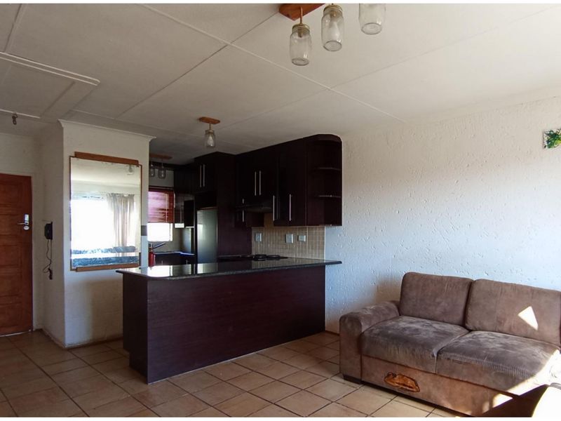 Open plan living area featuring a kitchen with dark wood cabinetry, granite countertops, and tiled flooring throughout.