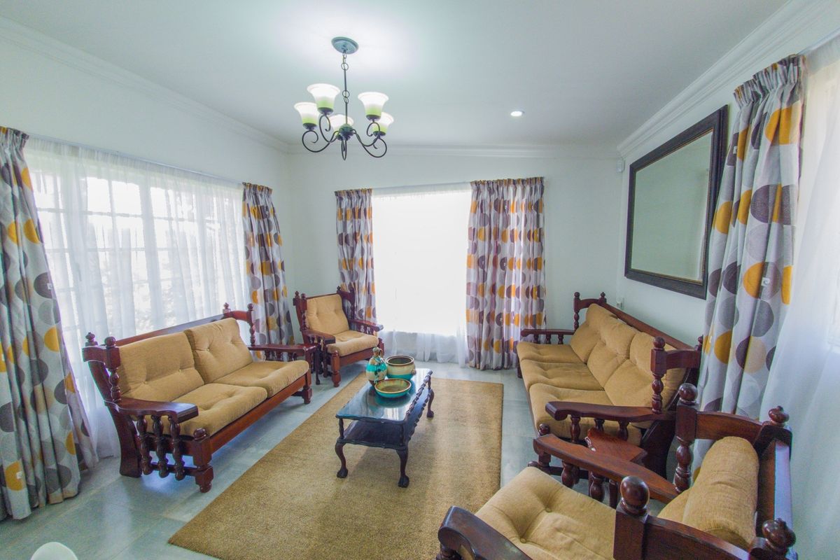 A well-lit living room featuring crown molding, a central chandelier, and tiled flooring, offering a comfortable and traditional living space.