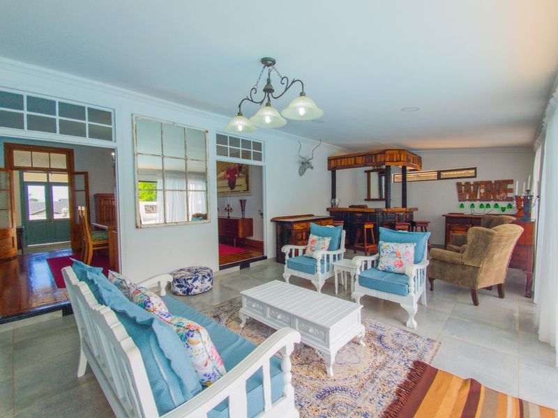Spacious living area featuring a built-in bar, tiled flooring, and classic transom windows, offering a comfortable and inviting space for relaxation and entertainment.