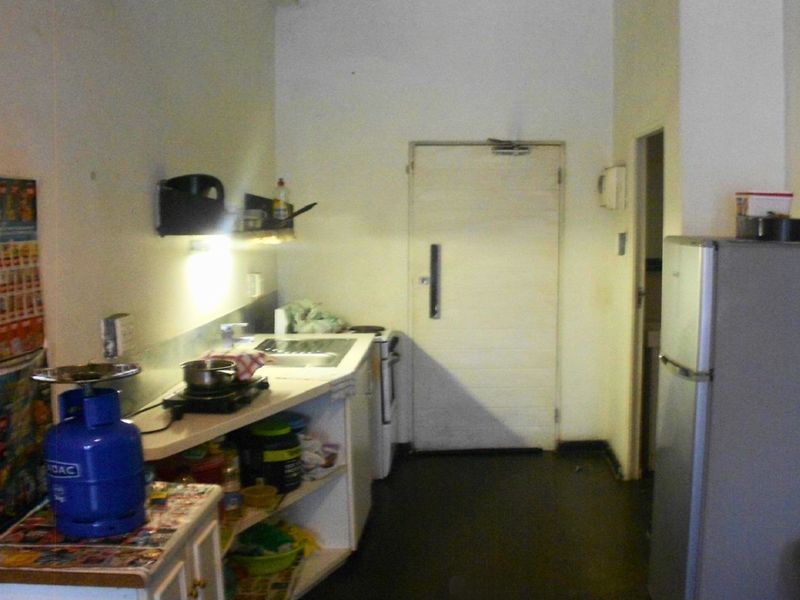 A compact kitchen area featuring basic cabinetry, a sink, and a functional layout, currently showing signs of wear and requiring cosmetic updates.