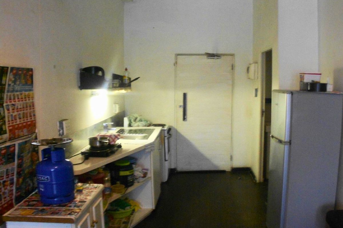 A compact kitchen area featuring basic cabinetry, a sink, and a functional layout, currently showing signs of wear and requiring cosmetic updates.