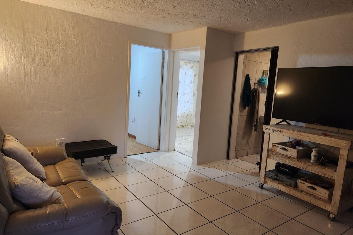 A living area featuring tiled flooring and access to adjacent rooms, including a bathroom with tiled finishes.