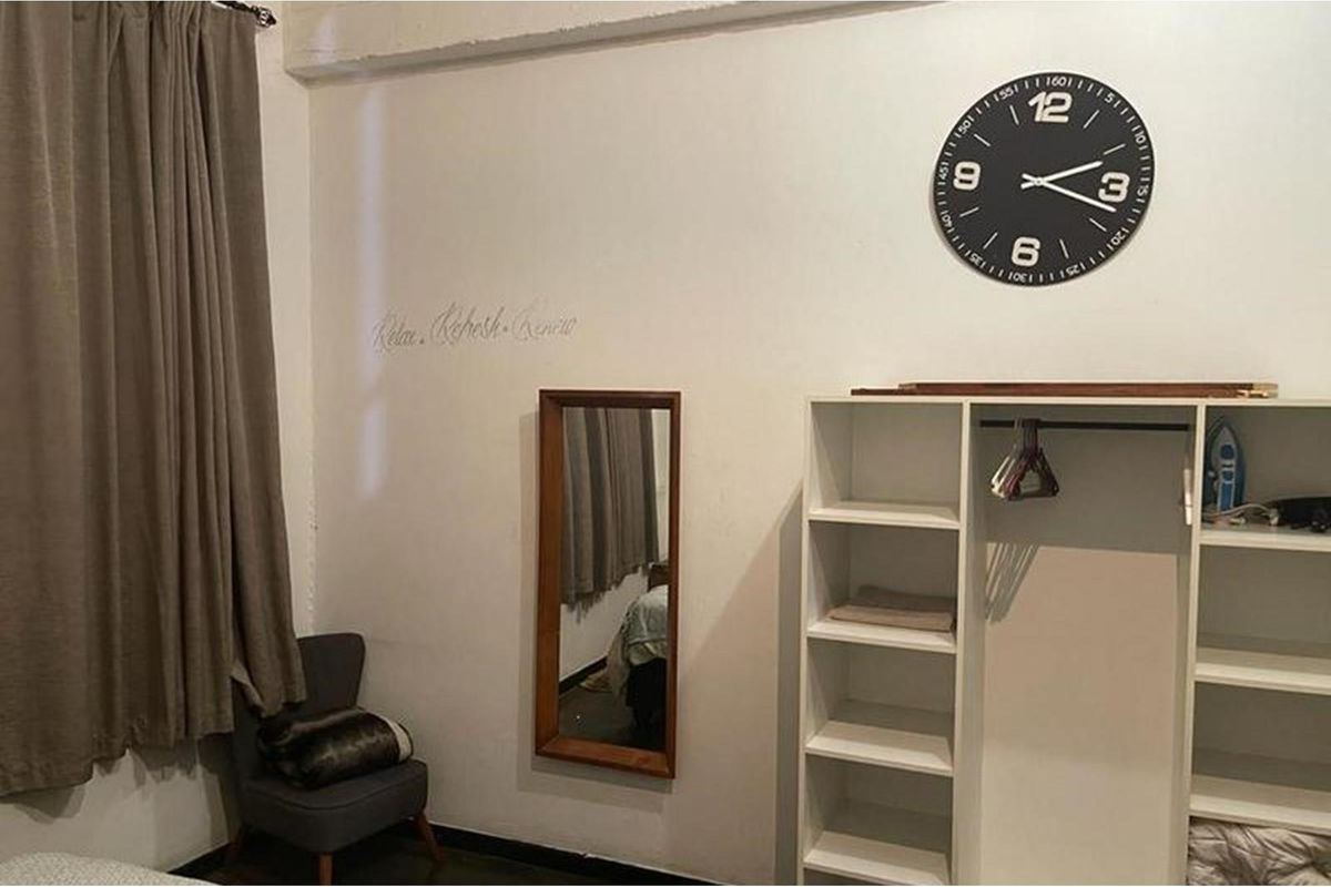 A bedroom featuring neutral walls, a built-in shelving unit, and a window with curtains.