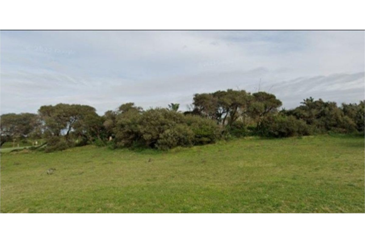 A view of a vacant residential plot featuring established trees and open grassy areas.