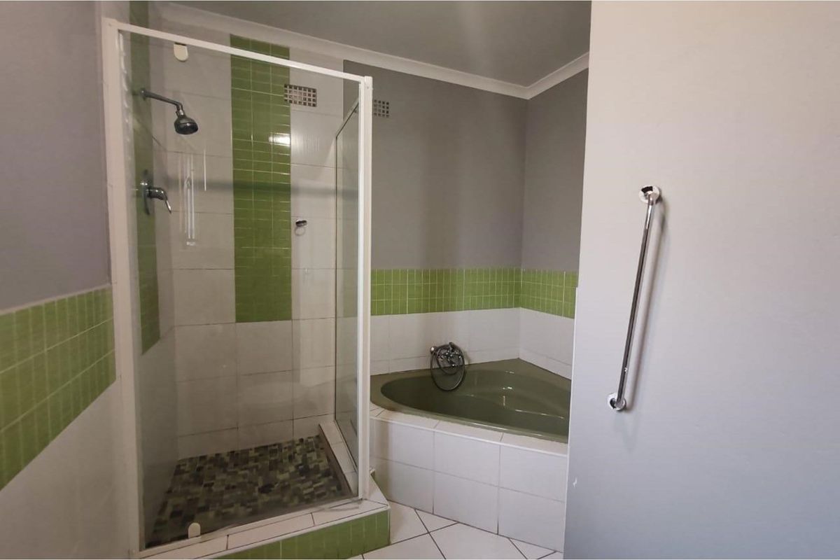 Bathroom featuring a corner bathtub, a separate glass-enclosed shower, and green accent tiling.