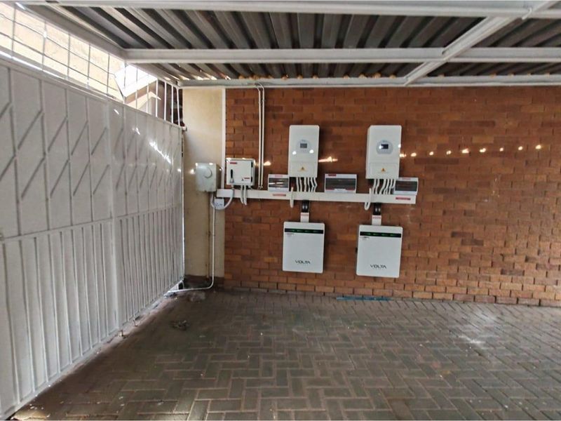 A covered garage area featuring a wall-mounted solar power system with two inverters and two battery storage units.