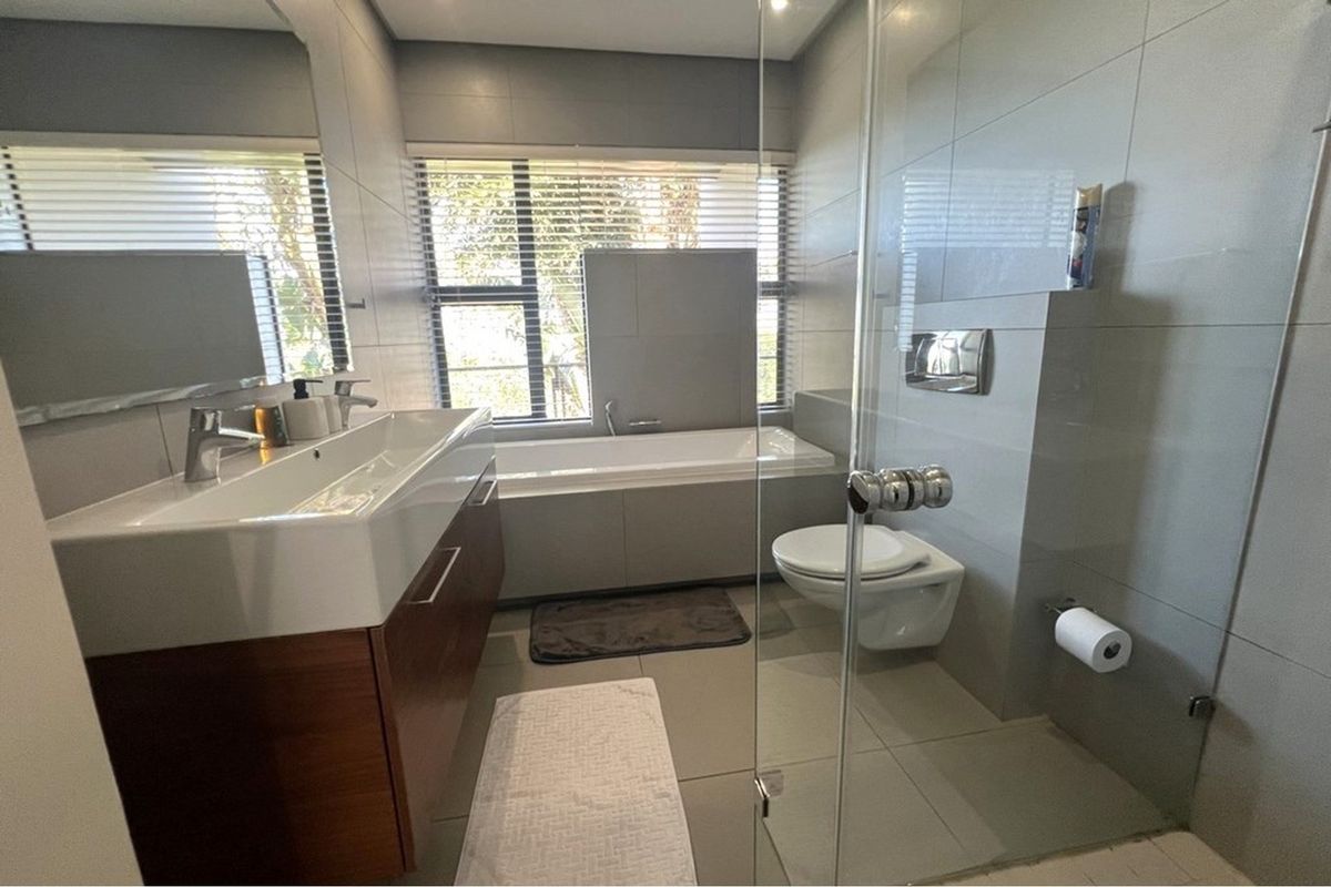 Modern bathroom featuring a wall-mounted vanity with integrated basin, wall-hung toilet with concealed cistern, and a built-in bathtub with tiled surround.