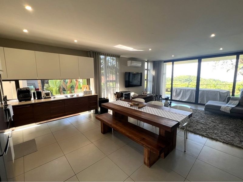Spacious open-plan living area featuring modern cabinetry, tiled floors, and large sliding glass doors that provide seamless access to the outdoor space.