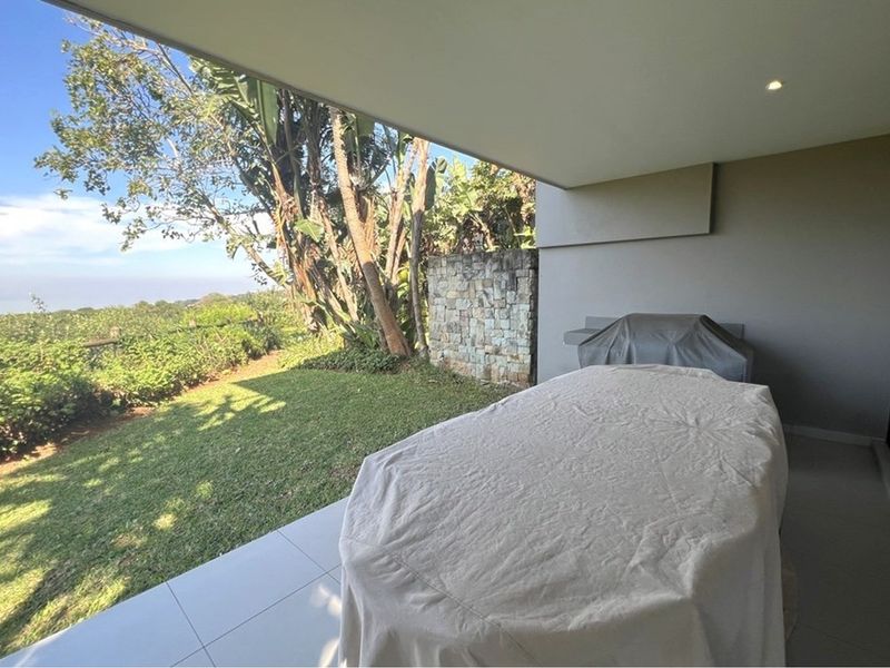 Covered patio featuring tiled flooring, recessed lighting, and a built-in braai, overlooking a landscaped garden with scenic views.