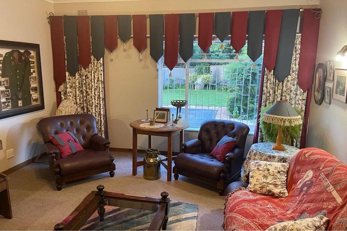 A cozy living room featuring a large window with security bars, overlooking a garden area.