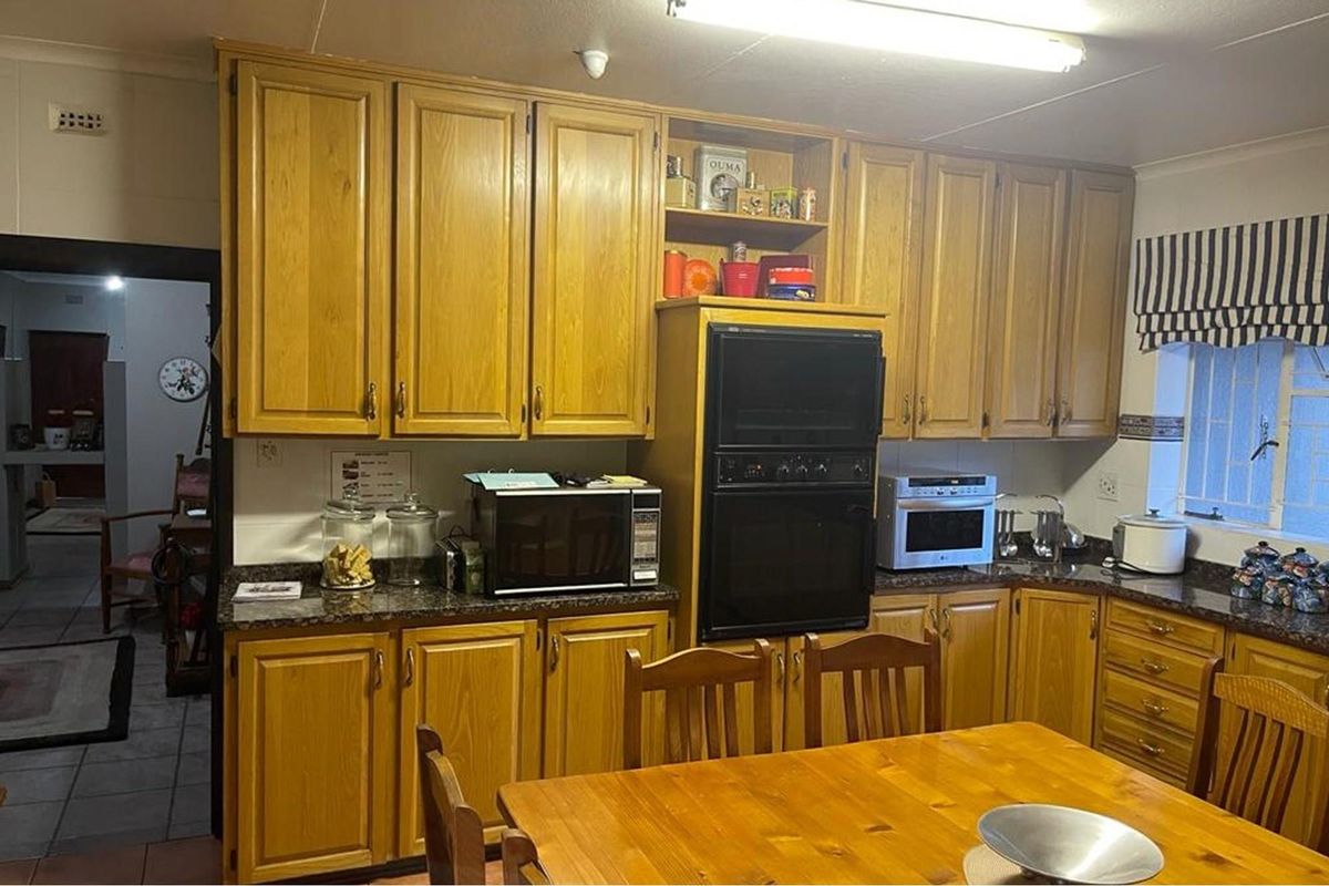A functional kitchen featuring traditional timber cabinetry, granite-look laminate countertops, and a built-in eye-level oven, offering a classic layout with ample storage space.