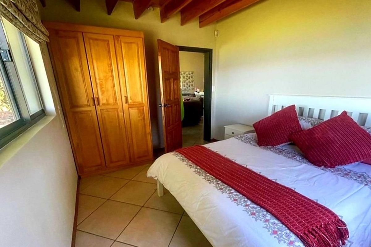 A bedroom featuring exposed timber ceiling beams, tiled flooring, and a built-in wooden wardrobe.