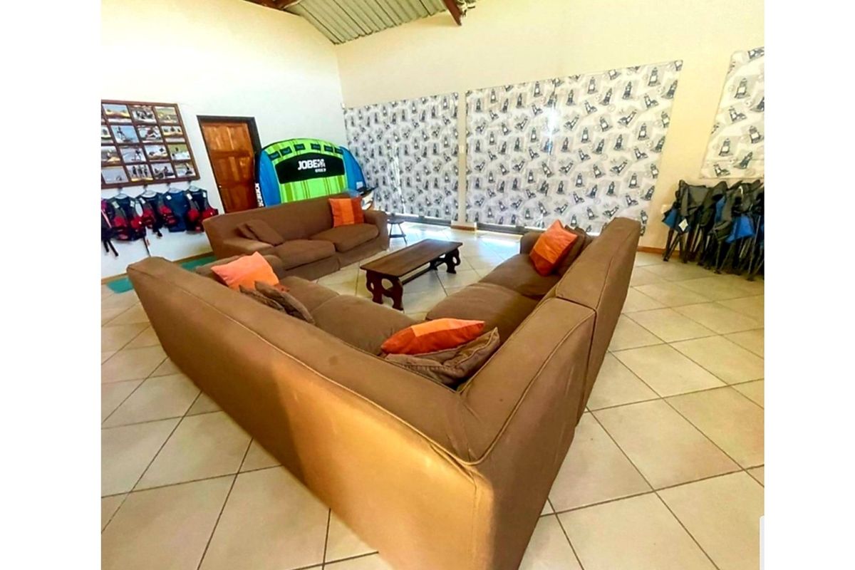 Spacious living area featuring tiled flooring, vaulted ceilings with exposed rafters, and large sliding glass doors providing natural light.