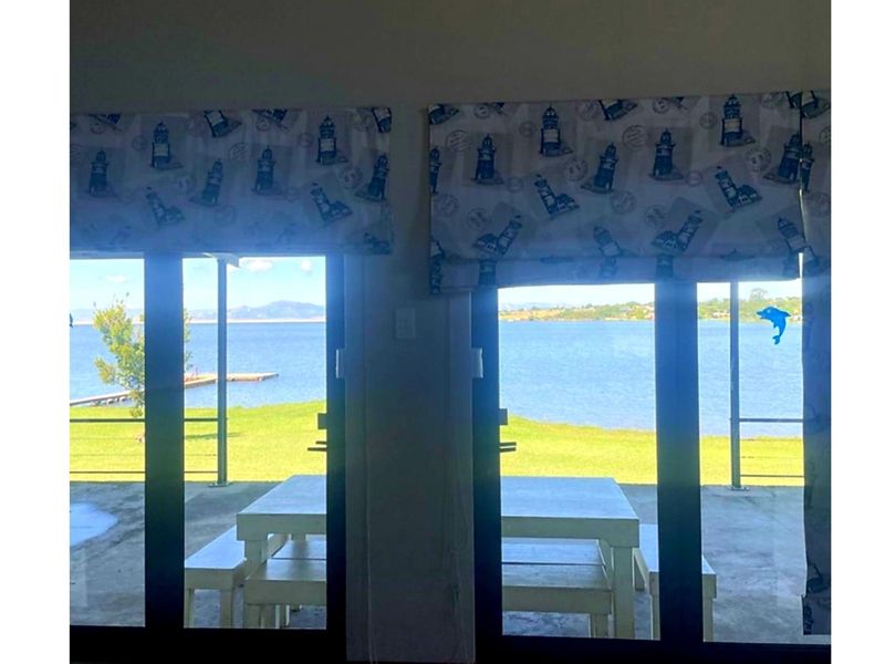 A view of the lake and jetty through large sliding glass doors leading to a covered patio area.
