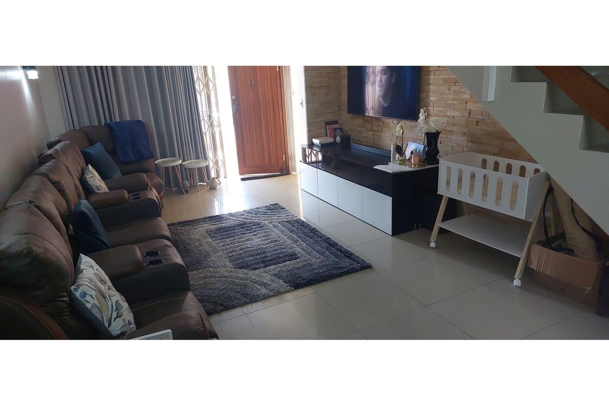 A living room featuring tiled flooring, a stone-cladding feature wall, and an open staircase, providing a functional and comfortable living space.