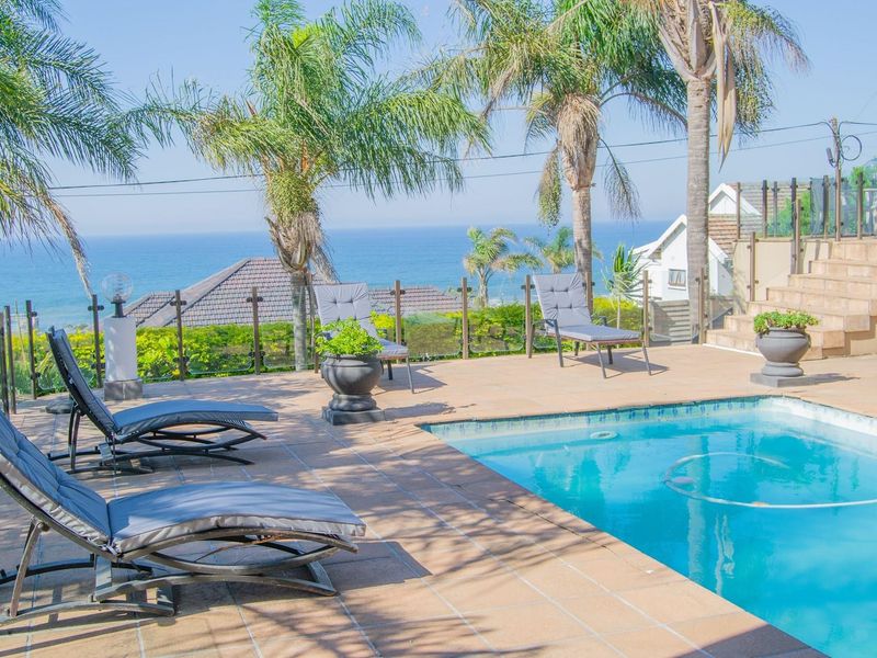 Outdoor pool area featuring a tiled deck, glass balustrade, and scenic ocean views, perfect for relaxation and entertainment.