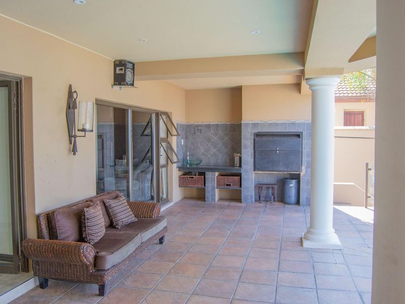 Covered patio area featuring a built-in braai, tiled flooring, and direct access to the interior through sliding glass doors.