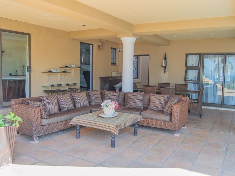 A spacious covered patio featuring tiled flooring, structural columns, and direct access to the interior through sliding glass doors.