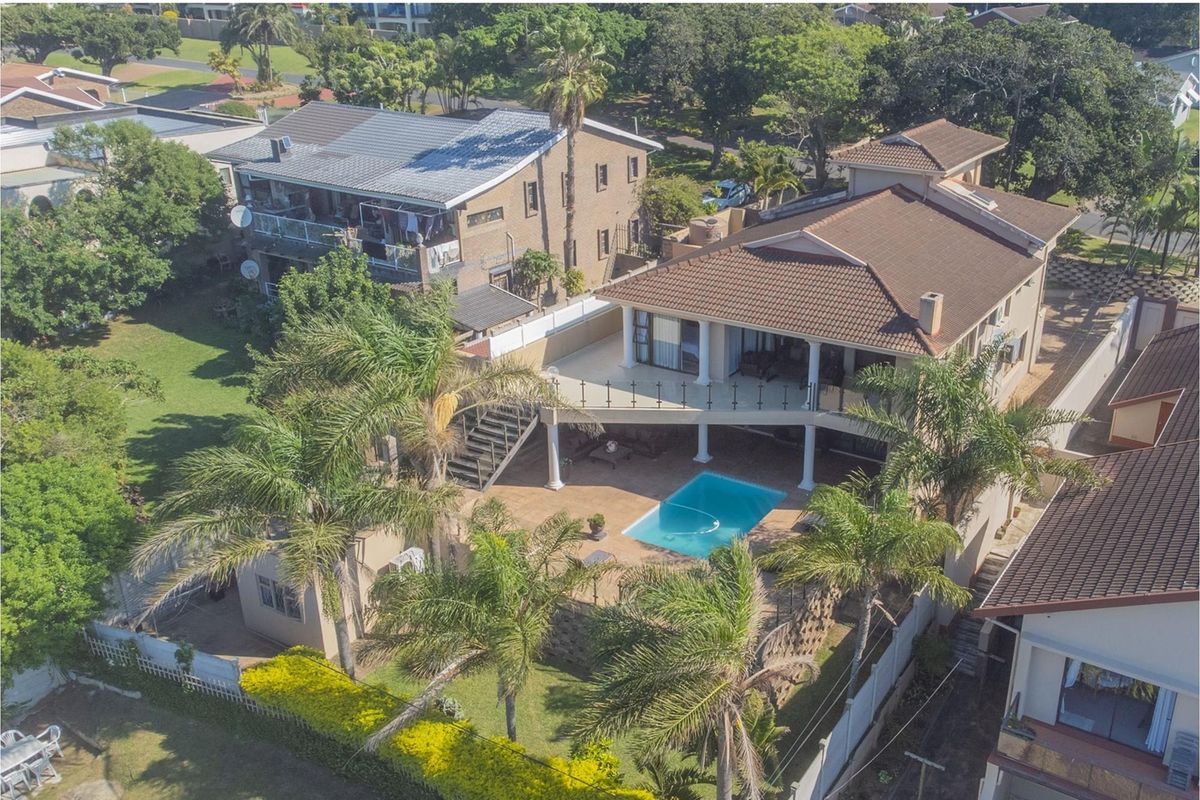 Aerial view of a multi-level residential property featuring a swimming pool, spacious elevated balcony, and landscaped garden area.