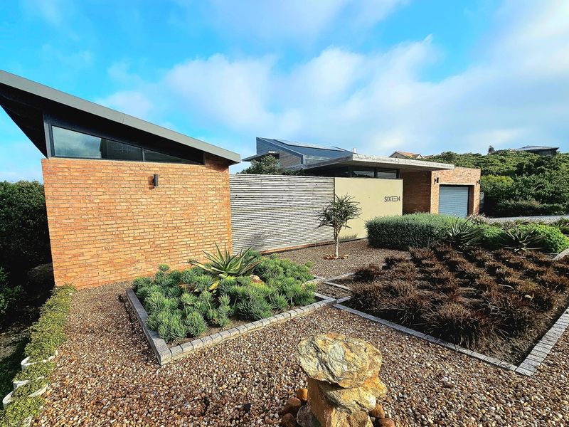 Modern architectural home featuring a striking brick facade, skillion roofline, clerestory windows, and a well-maintained landscaped garden with gravel driveway.