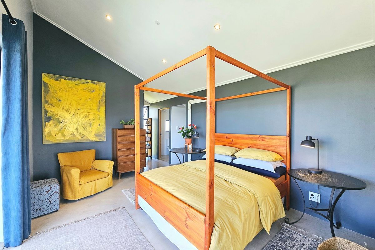 Spacious bedroom featuring polished concrete flooring, recessed downlighting, and a contemporary dark feature wall.