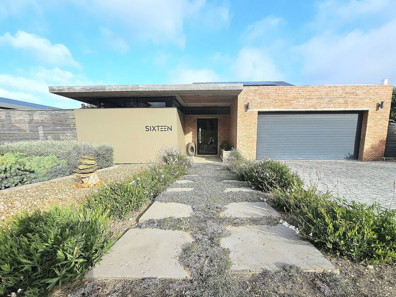 Modern single-story residence featuring a brick facade, integrated garage, solar panels, and a well-maintained landscaped front garden with a stone pathway.