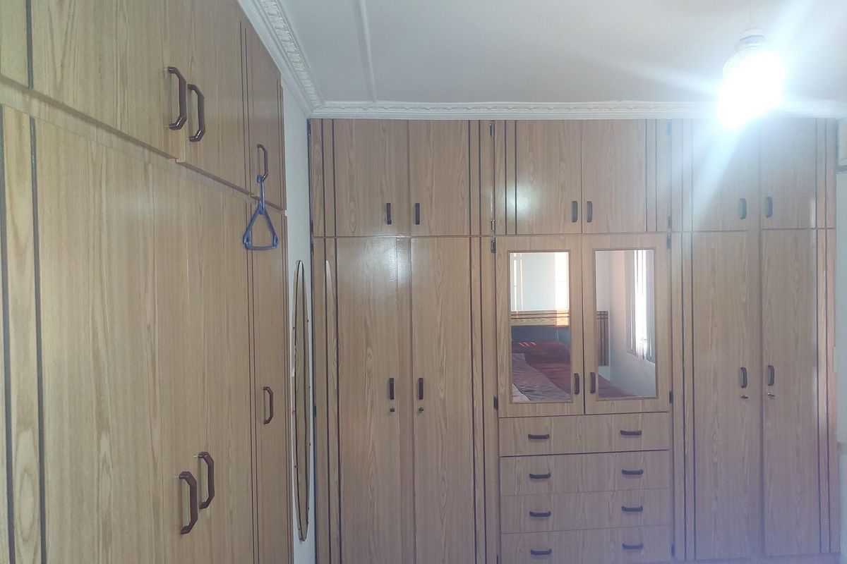 A bedroom featuring extensive floor-to-ceiling built-in wooden cabinetry with integrated drawers and mirror panels.