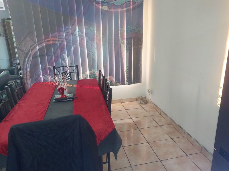 A dining area featuring tiled flooring and vertical blinds, providing a functional space for meals.