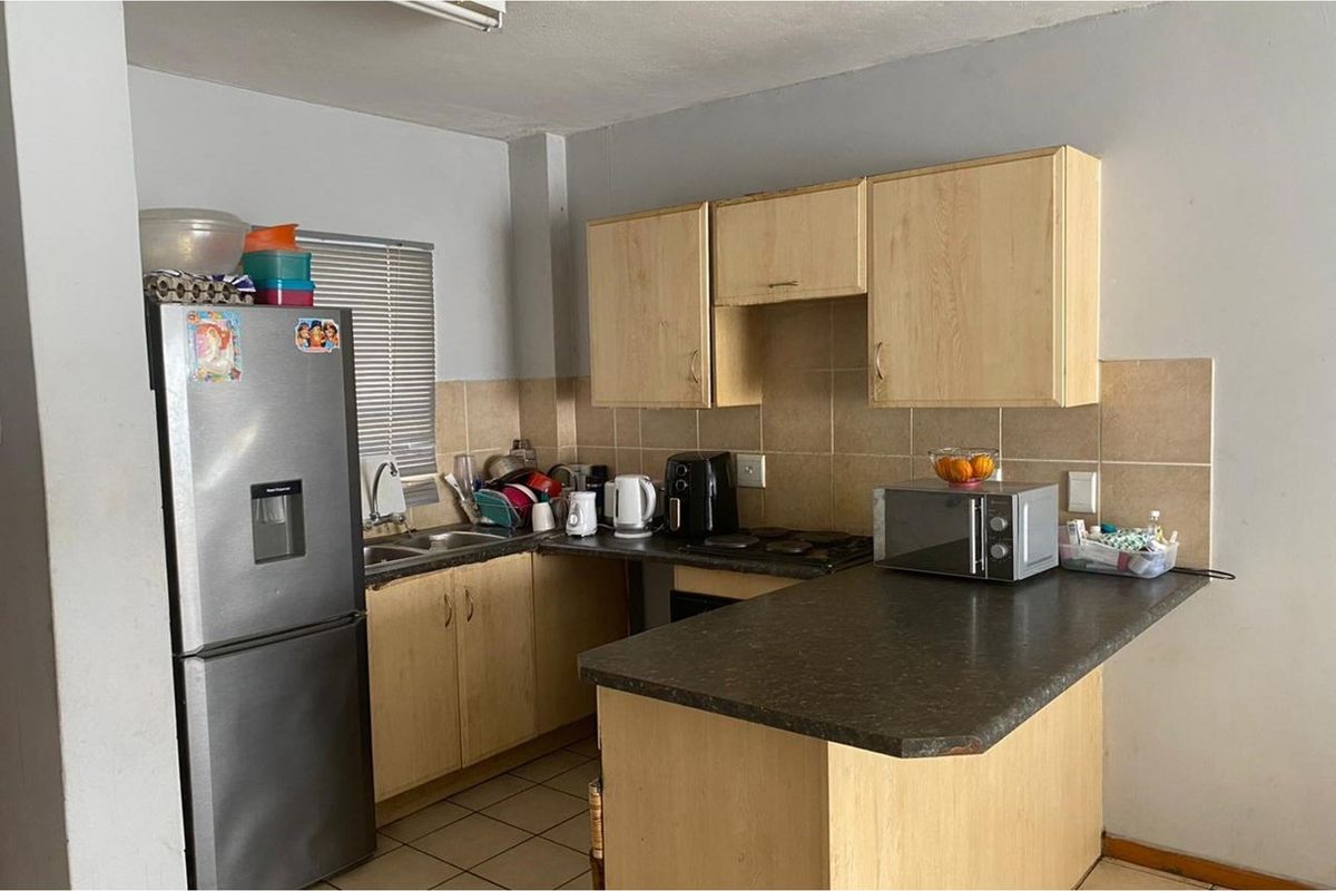 A functional kitchen featuring laminate cabinetry, tiled backsplash, and a breakfast counter, offering a practical layout for daily meal preparation.
