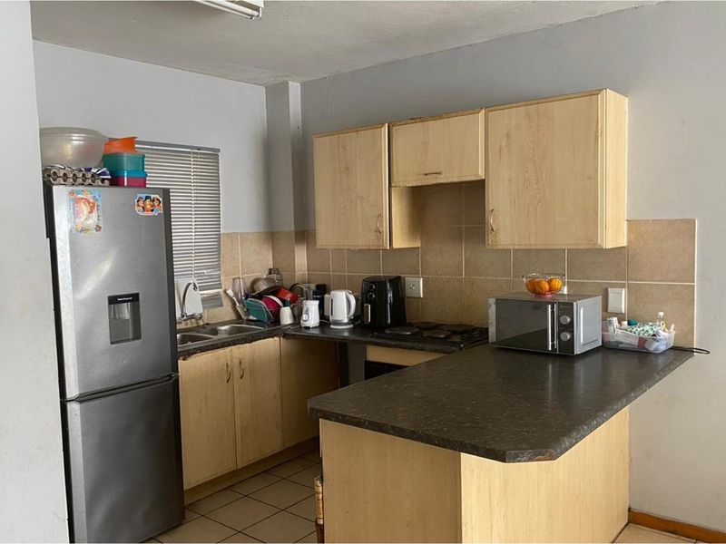 A functional kitchen featuring laminate cabinetry, tiled backsplash, and a breakfast counter, offering a practical layout for daily meal preparation.
