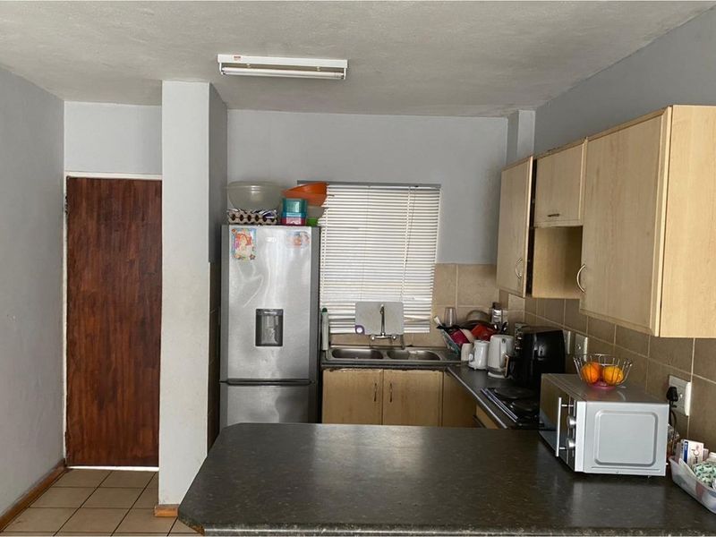 A functional kitchen featuring laminate cabinetry, a double bowl sink, tiled backsplash, and a breakfast bar counter.