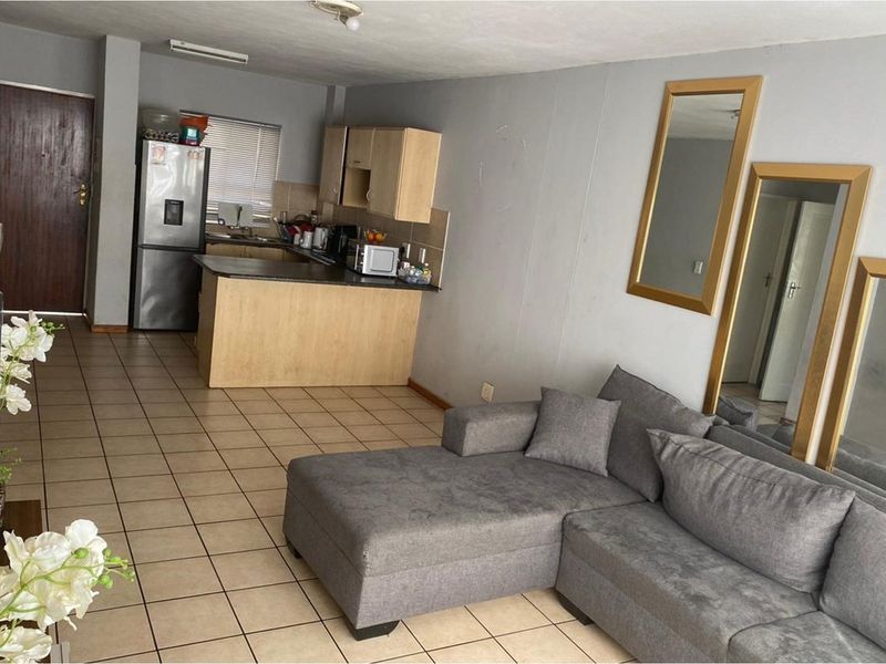 Open-plan living area featuring tiled flooring and a functional kitchen with built-in cabinetry and countertop space.