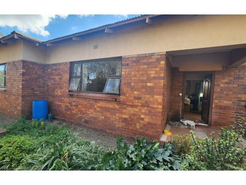 Rear exterior view of a face brick house featuring a covered entrance porch and aluminium window frames.