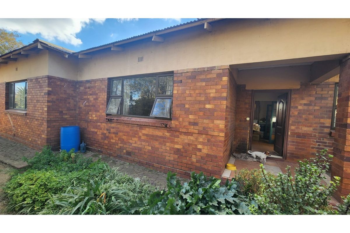Rear exterior view of a face brick house featuring a covered entrance porch and aluminium window frames.