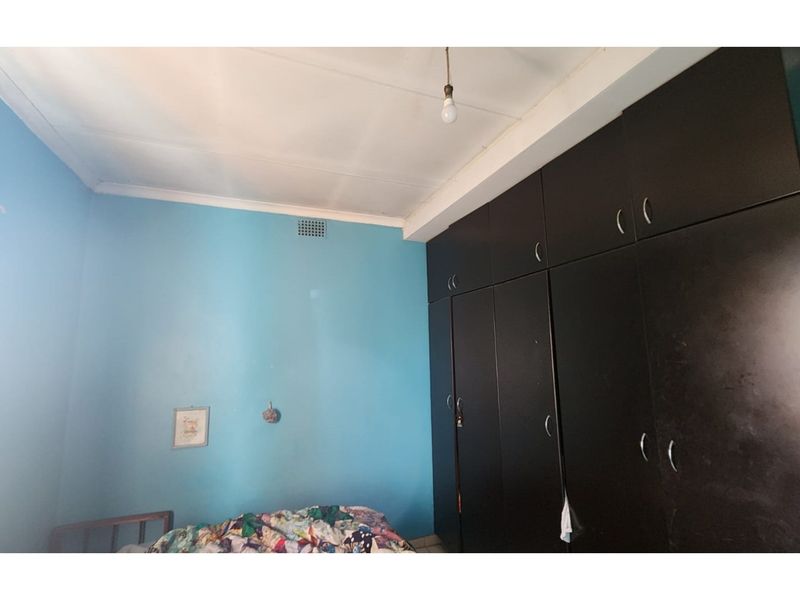 A bedroom featuring blue walls and extensive dark-toned built-in cupboards providing ample storage space.