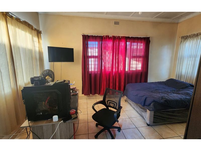 A bedroom featuring tiled flooring and a ceiling vent, requiring cosmetic updates to the walls and ceiling to improve the overall aesthetic.
