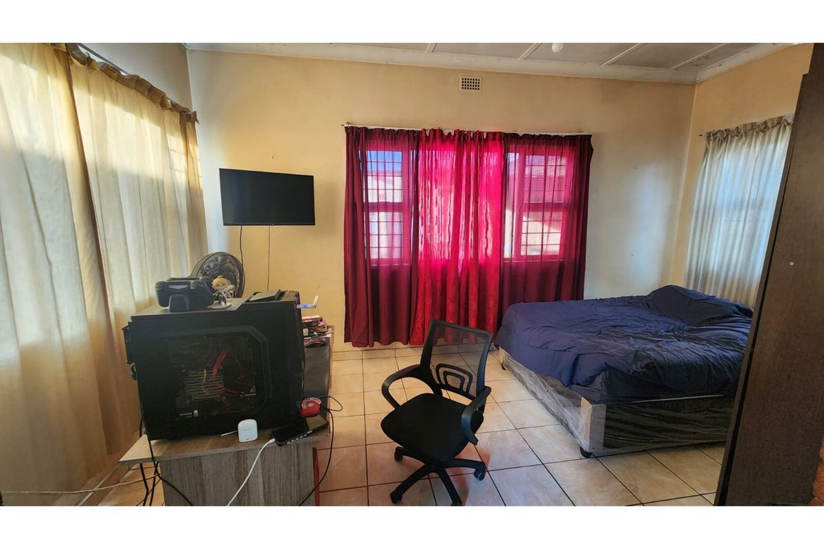 A bedroom featuring tiled flooring and a ceiling vent, requiring cosmetic updates to the walls and ceiling to improve the overall aesthetic.