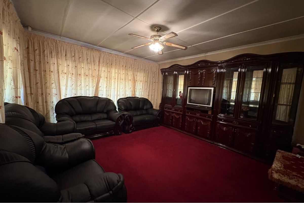 A traditional living room featuring a large built-in wooden wall unit, ceiling fan, and wall-to-wall carpeting.