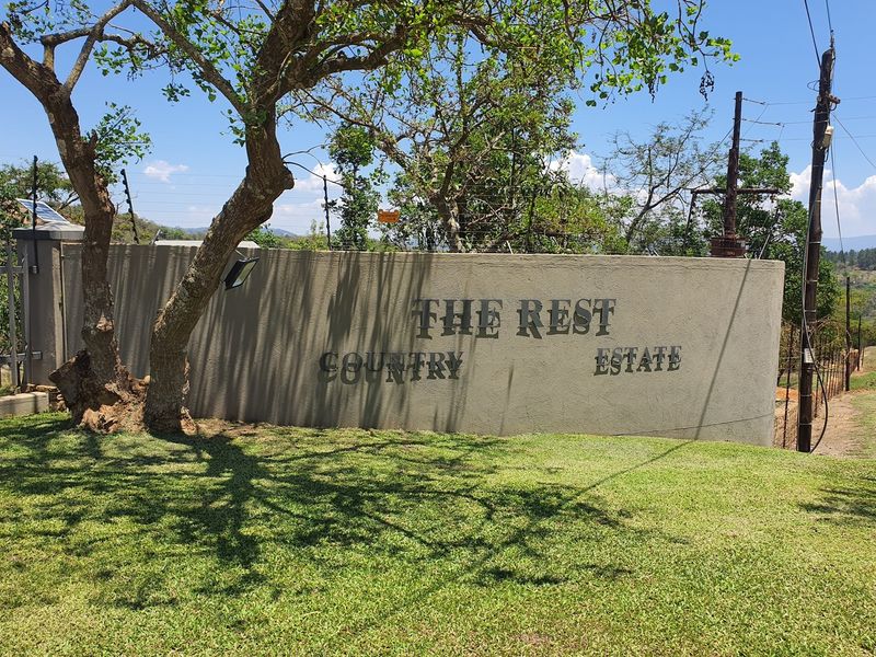 Entrance signage and perimeter wall for The Rest Country Estate, featuring established trees and landscaped grass verge.
