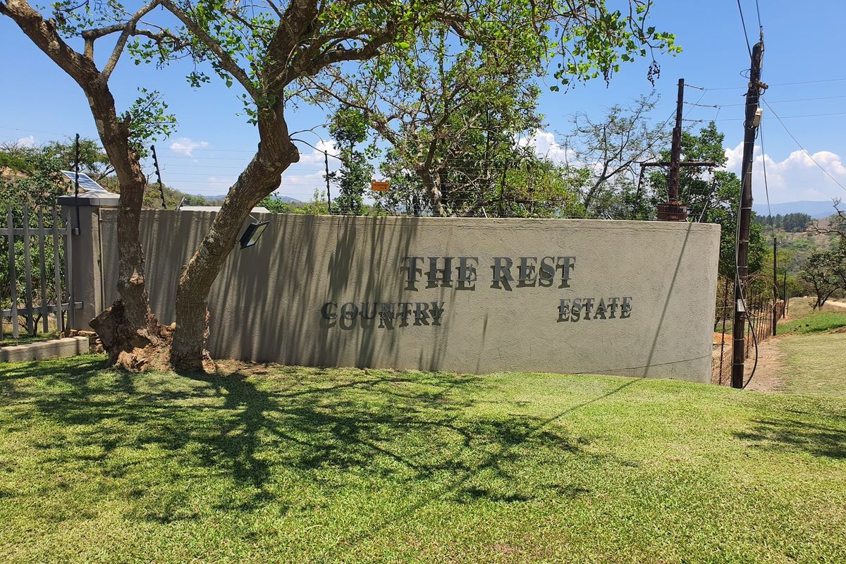 Entrance signage and perimeter wall for The Rest Country Estate, featuring established trees and landscaped grass verge.