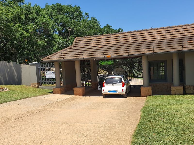 A secure gated entrance to the residential estate featuring a tiled roof structure, stone-clad pillars, and an automated security gate.