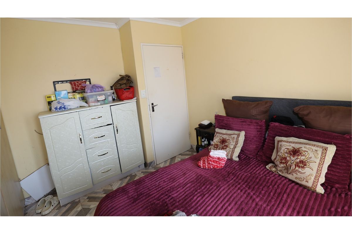 A bedroom featuring patterned flooring and neutral wall tones, providing a functional space for rest.
