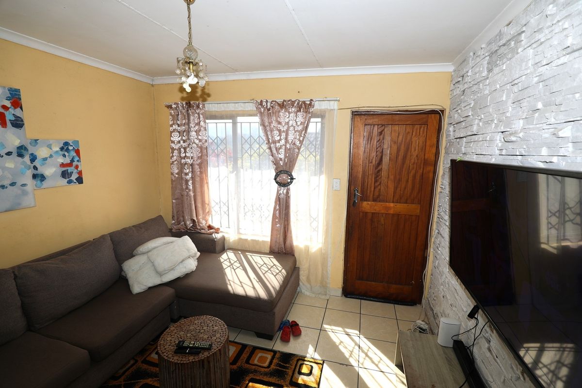A cozy living room featuring a textured stone feature wall, tiled flooring, and a wooden entrance door.