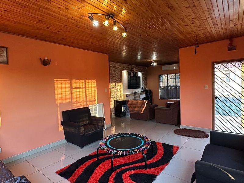 Spacious living room featuring a timber ceiling, tiled flooring, and a stone feature wall, providing a comfortable and functional family living space.