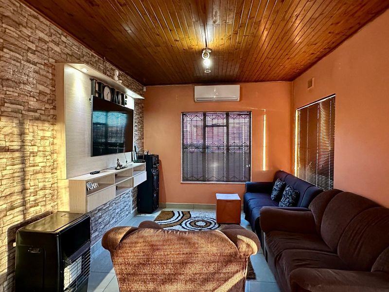 A living room featuring a timber-clad ceiling, stone veneer feature wall with built-in media cabinetry, tiled flooring, and a wall-mounted air conditioning unit.