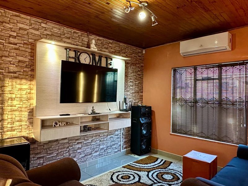 Living room featuring a timber ceiling, stone veneer feature wall, built-in media console, and a split-system air conditioner.