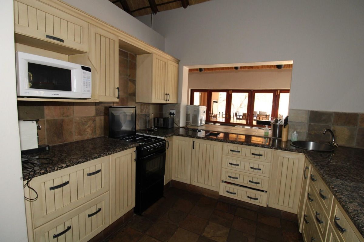 A functional kitchen featuring granite countertops, built-in cabinetry, a freestanding stove, and a pass-through window overlooking the adjacent living area.
