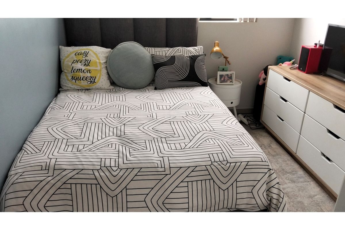 A well-maintained bedroom featuring a neutral color palette, carpeted flooring, and a built-in headboard.